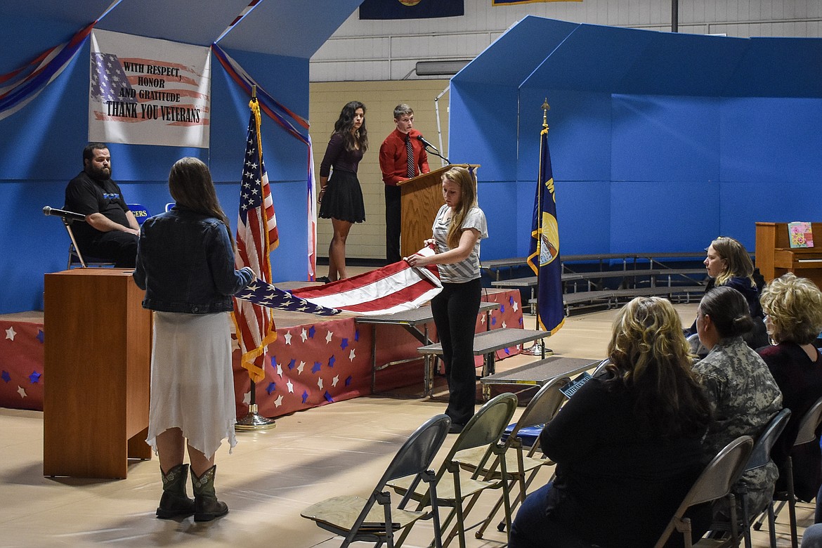 Brandy Murray and Cerria Swagger perform a flag folding ceremony before presenting the flag to guest speaker and U.S. Marine Corps veteran Ramsey Smith during the Veterans Day observance in the Ralph Tate Memorial Gymnasium at Libby High School Monday. (Ben Kibbey/The Western News)