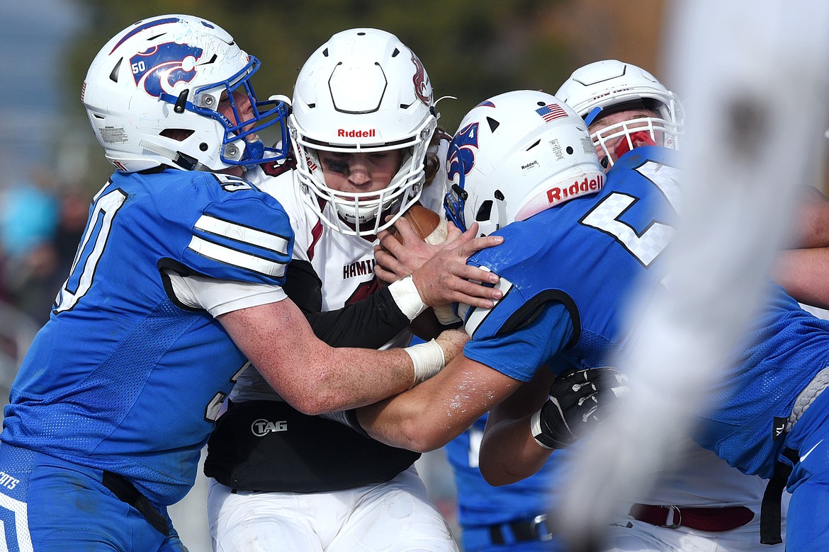 Hamilton quarterback Carson Rostad (3) is sandwiched by Columbia Falls defenders Tanner Gove (50) and Brad Nieves (54) on a first-quarter run in a Class A semifinal playoff game at Columbia Falls High School on Saturday. (Casey Kreider/Daily Inter Lake)