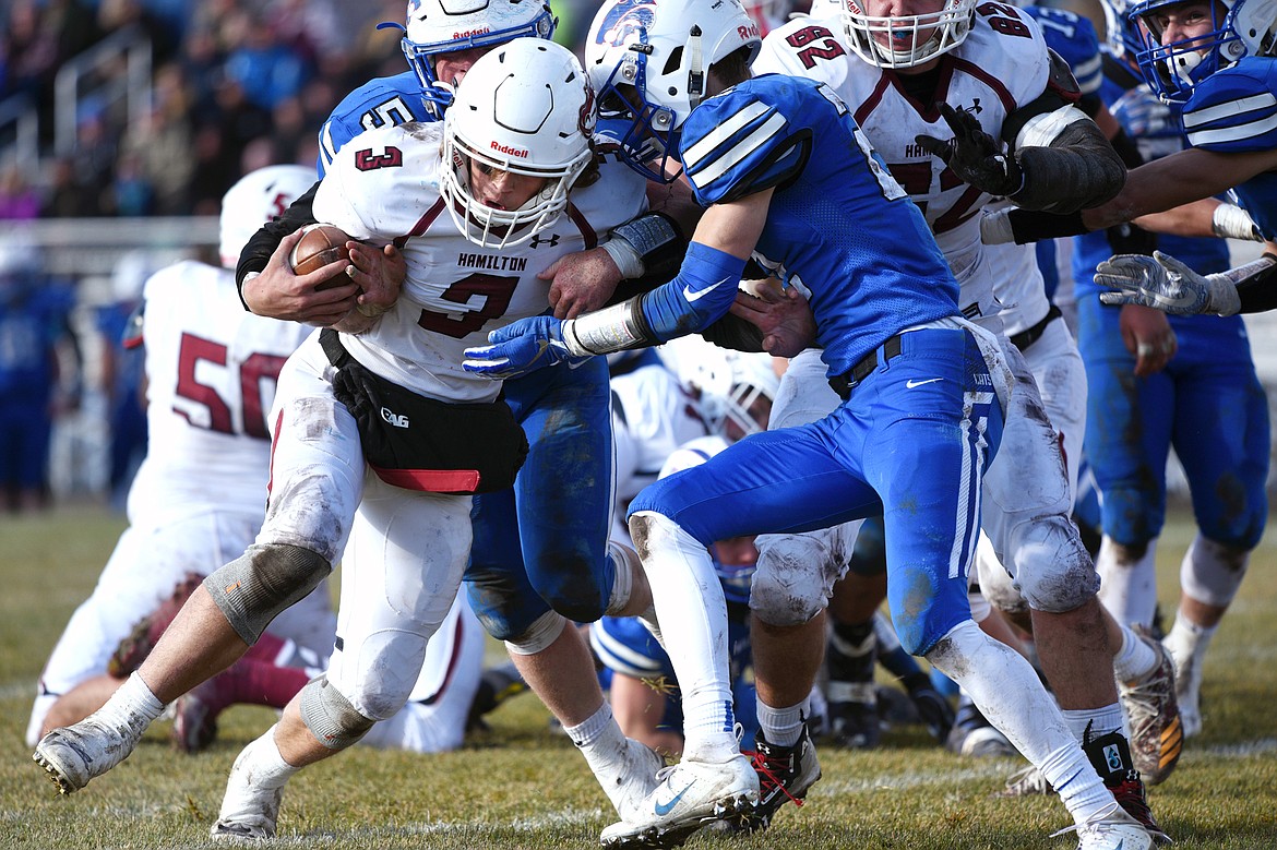 Hamilton quarterback Carson Rostad (3) is brought down by Columbia Falls defenders Tanner Gove (50) and Lane Sapa (22) on a second quarter run in a Class A semifinal playoff game at Columbia Falls High School on Saturday. (Casey Kreider/Daily Inter Lake)