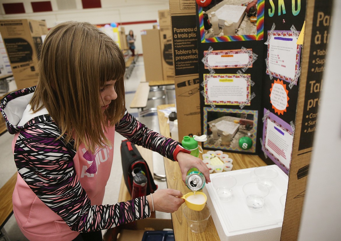 LOREN BENOIT/Press
Canfield Middle School sixth-grader Mari Nelson pours 7UP into a measuring cup before dropping Skittles candies into cups for her science project. Mari&#146;s experiment explored how fast it takes a Skittles candy to dissolve in different solutions.