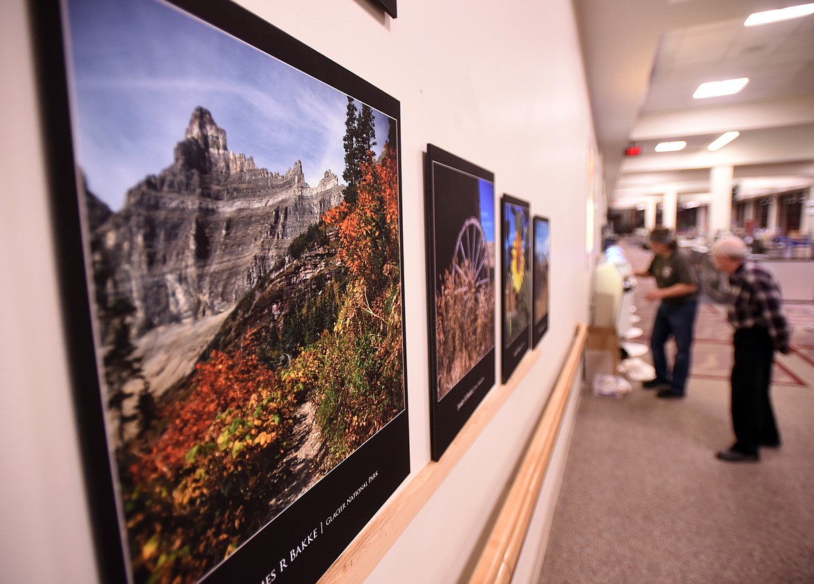 Bret Bouda and Terry Abell hanging work by James R. Bakke at the Glacier Park International Airport on Monday evening, November 19.(Brenda Ahearn/Daily Inter Lake)