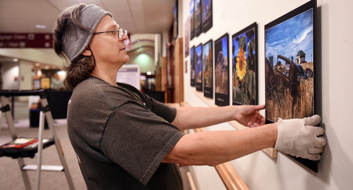 Bret Bouda hanging work by James R. Bakke at the Glacier Park International Airport on Monday evening, November 19.(Brenda Ahearn/Daily Inter Lake)