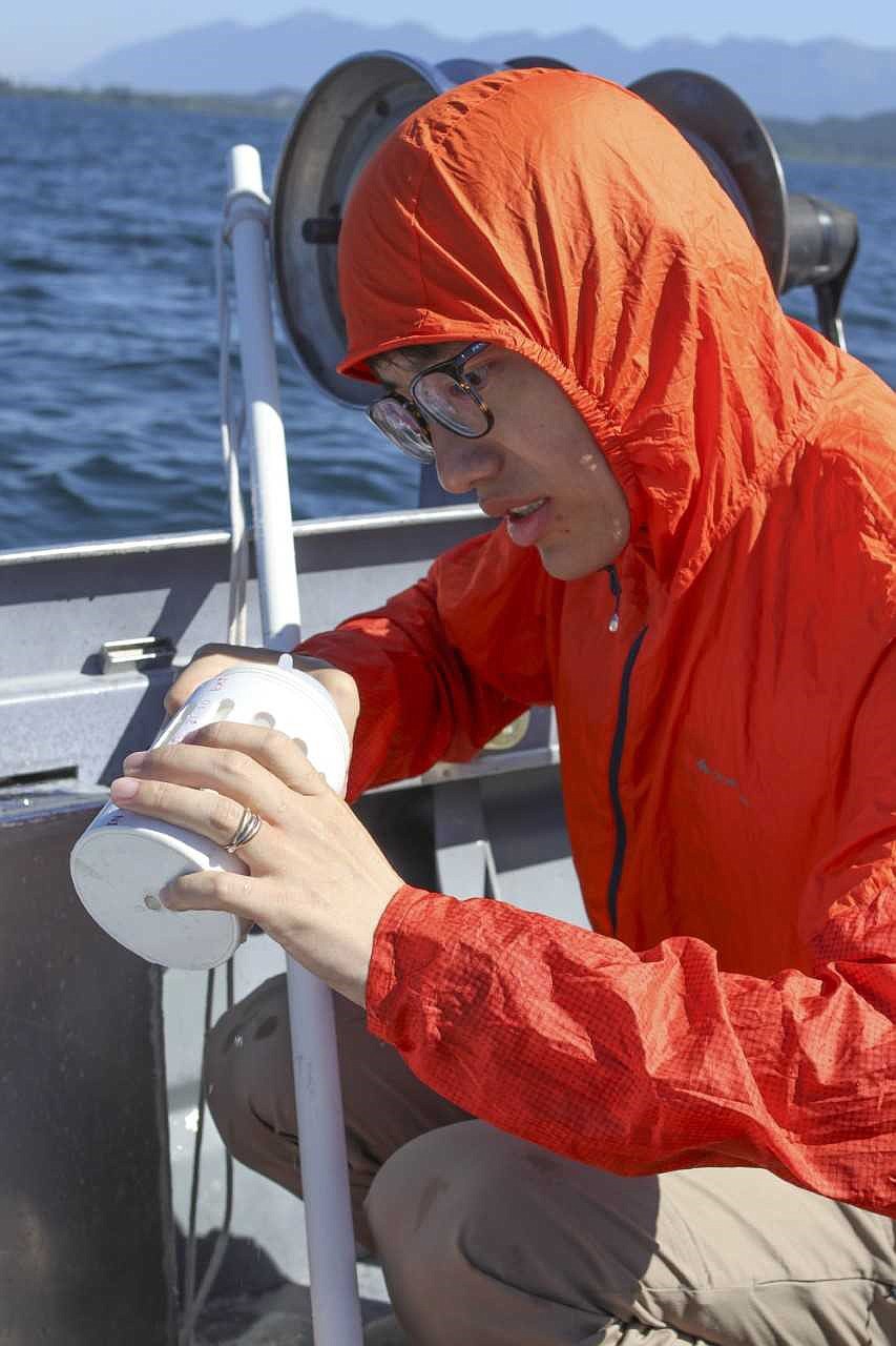 Researcher Xiong Xiong takes the first water samples looking for microplastics in Flathead Lake. In one of his 12 samples, he found a large piece of plastic several inches long. (Photo by Heather Fraley)