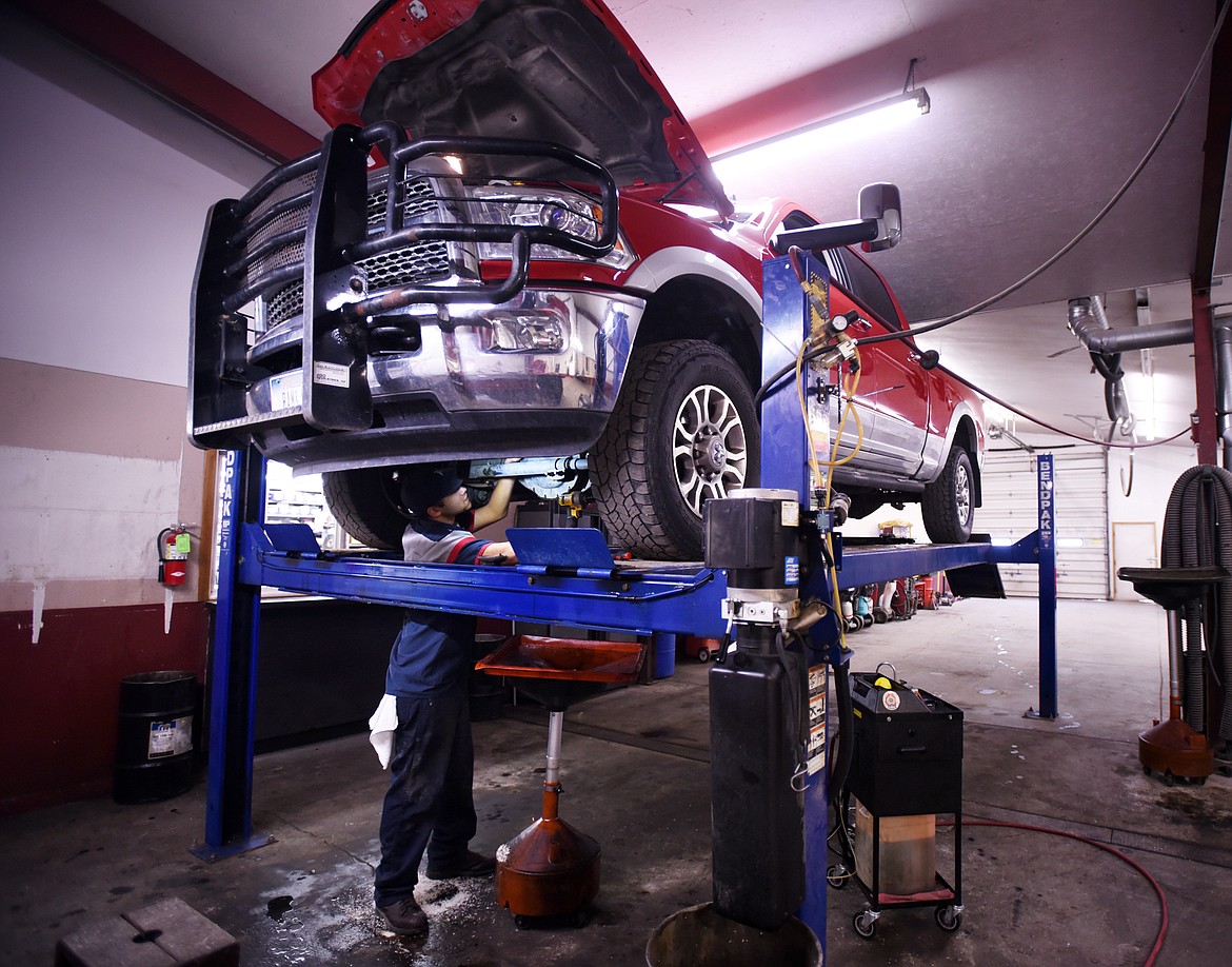 A mechanic works under a truck at Ronan Motors.