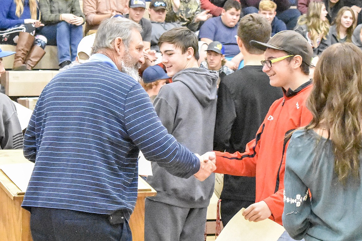 Libby High School golf Head Coach Dann Rohrer congratulates freshman Eric Vinion, recipient of the &#147;Most Improved&#148; team award for the boys golf team during the Fall Awards Assembly Thursday. (Ben Kibbey/The Western News)