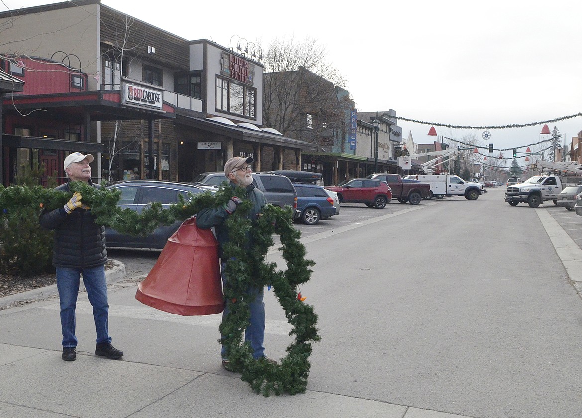 Jim Trout, left, and Mike Muldown hold up a section of garland Sunday morning on Central Avenue. (Heidi Desch/Whitefish Pilot)