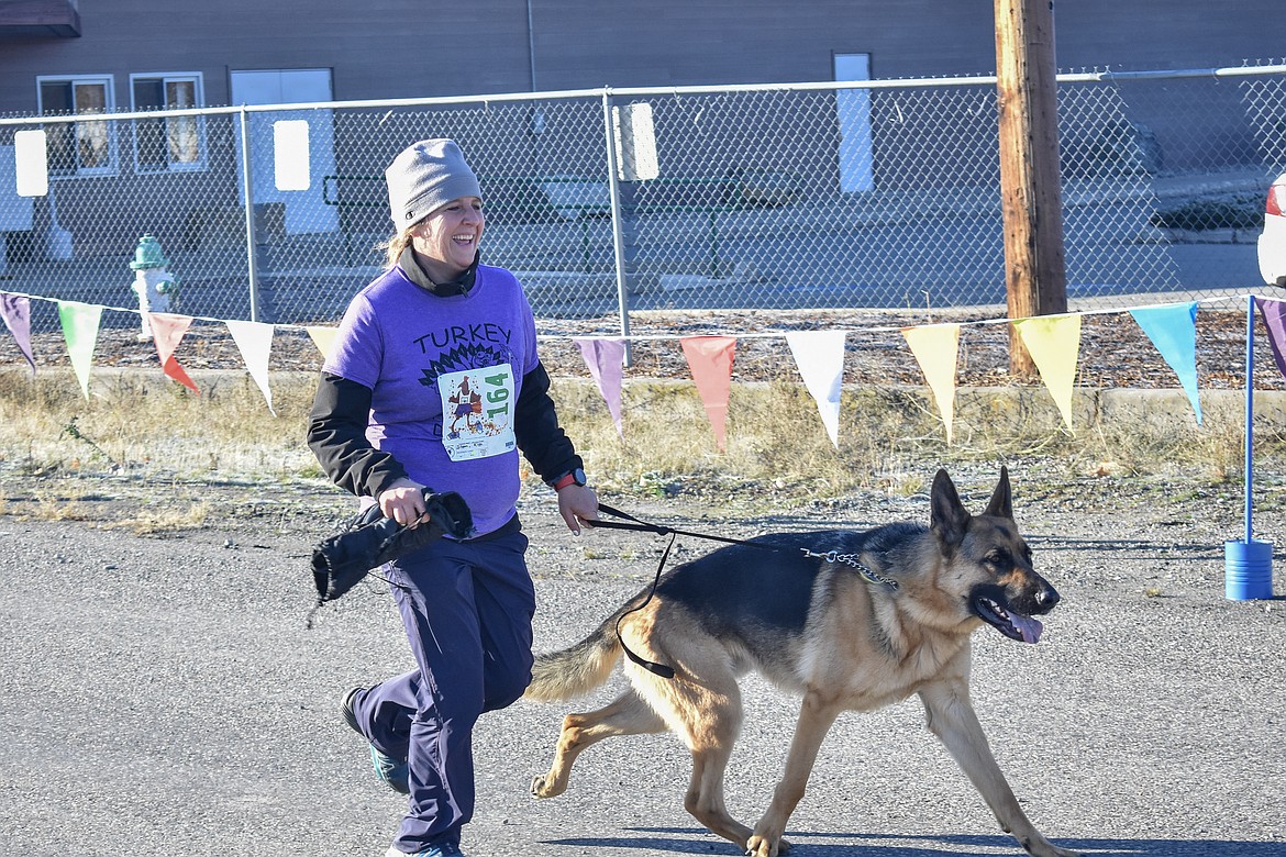 Kim Sloan reaches the finish line with her German shepherd leading the way during the Turkey Dash 5k fun run on Saturday, Nov 17. (Ben Kibbey/The Western News)