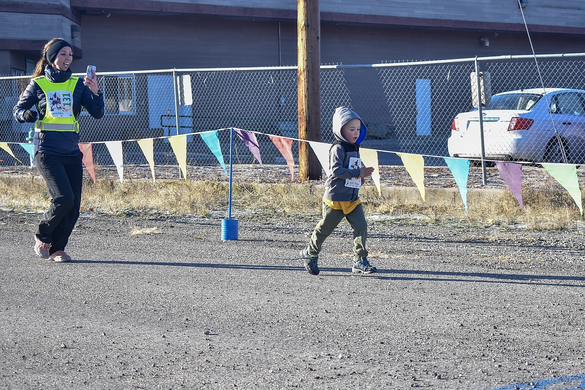 Brittany Katzer catches a shot of Waylon Katzer with her phone as they reach the finish line. (Ben Kibbey/The Western News)