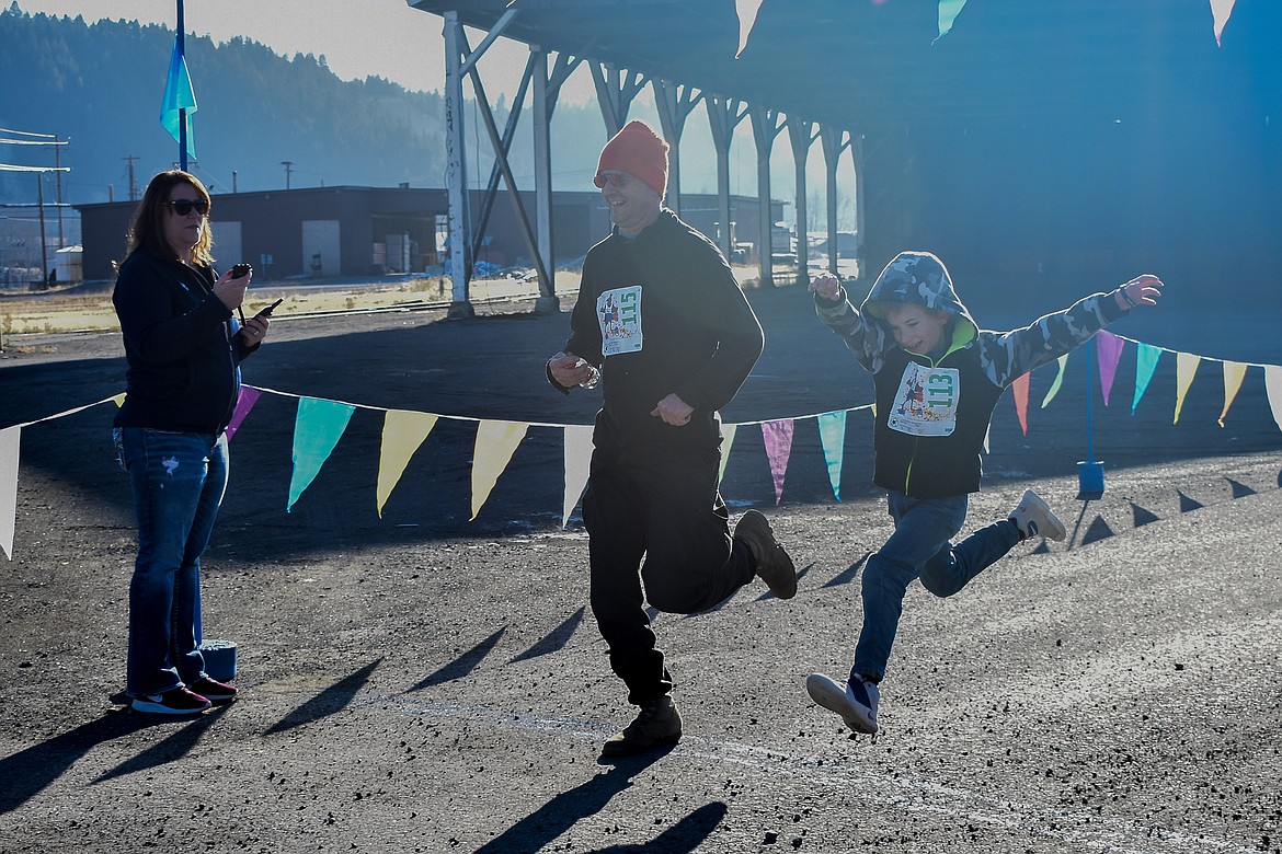Ben France does a final leap to cross the finish line alongside Mike France during the Turkey Dash 5k fun run/walk. (Ben Kibbey/The Western News)
