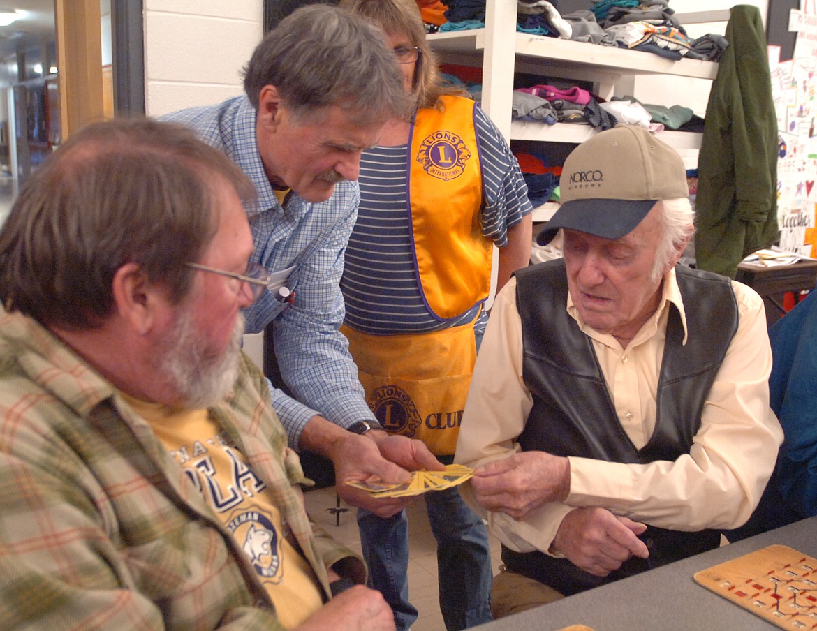 CHARLES PATTON draws a playing card from Hot Springs Lions Club member Lawrence Walchuk during the OGNIB fundraiser Sunday. Patton was the winner of one of the games and took home a turkey. Also pictured is OGNIB player Keith Joiner and Lions member Valerie Sidmore.