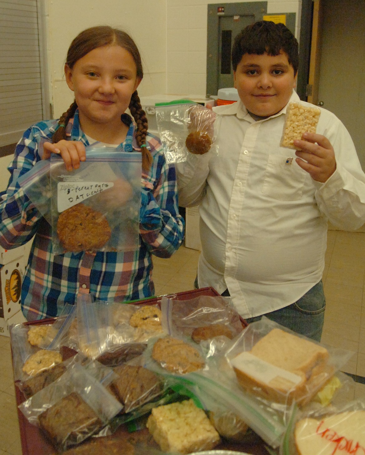 Ashlynn Rexus, left, and Jamason Harris show the snacks they were selling during the OGNIB fundraiser. Sales that they and their teammates raised help fund the Lutheran and Presbyterian United Church after-school program in Hot Springs.