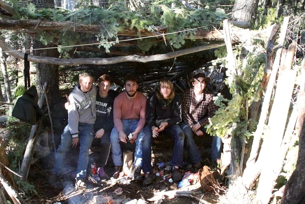 Photo by SHERRY LEITZ/ 
(Left) Matthew Peite, Chandler Holling, Skye Gallaway, Kash Truitt and Josh Williams sit under their lean-to in front of the fire.