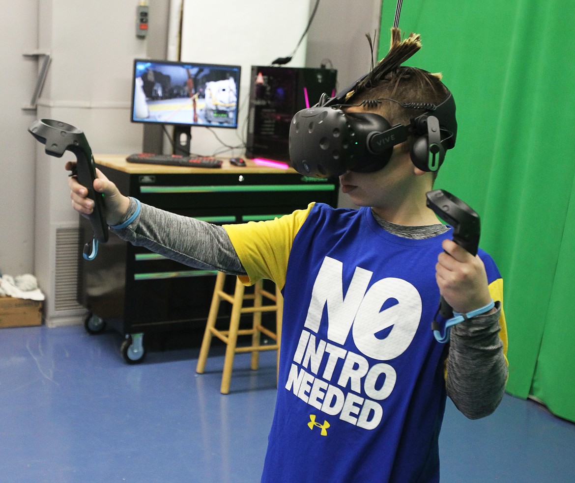 Gage McWatters, 9, of Rathdrum, uses the HTC Vive virtual reality headset to maneuver a virtual bow and arrow in Gizmo-CDA's VR lab Saturday. Visitors were invited to try out different devices and see how new tech works during the immersive technology day, which took place at the end of the week-long  d'Alene technology celebration. (DEVIN WEEKS/Press)