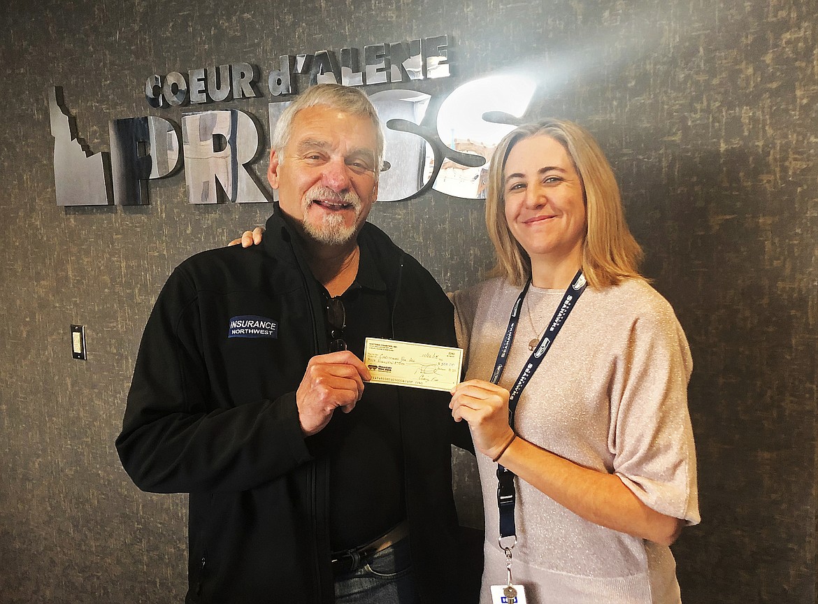 Press employee and Christmas for All volunteer Brandi Beer gratefully accepts a check for $500 from John Goedde, representing Kootenai Charities, Inc. Goedde and Kootenai Charities are longtime donors to the annual holiday fundraiser. (MIKE PATRICK/Press)