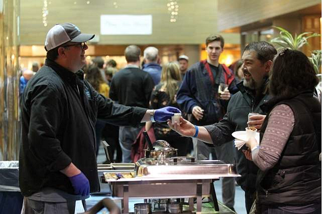 DEVIN WEEKS/BJNI file
Chris White, general manager and chef of Cosmic Cowboy, hands a cup of pork belly mac and cheese to festival-goer Jarred Perona, with wife Holly, during the Coeur d&#146;Alene Downtown Association&#146;s inaugural Mac and Cheese Festival in The Resort Plaza Shops in January 2018. The event was a huge hit and will return this month for locals and tourists to enjoy.