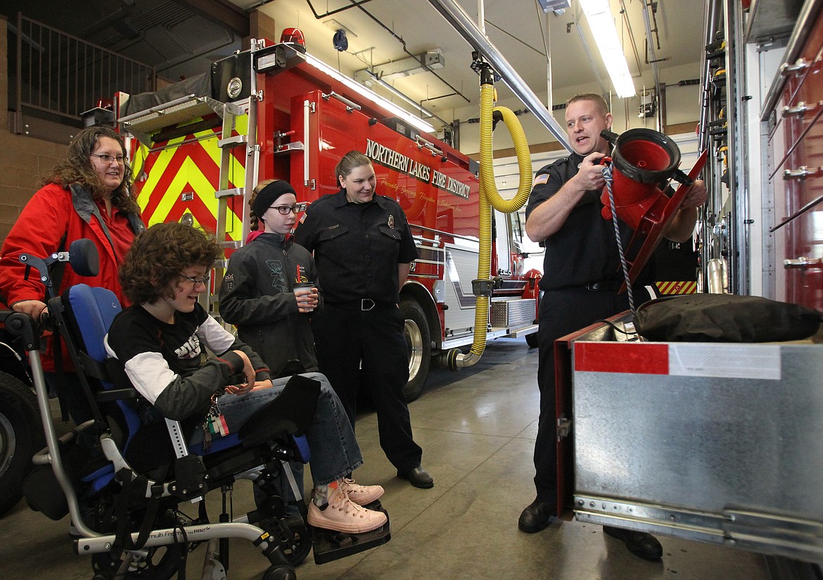 Northern Lakes Fire engineer and paramedic Chris Larson teaches fifth-graders Abby Van Cleve, left, and Taylor Howe about firefighter equipment during a visit to the Rathdrum station Saturday morning. Taylor knows Abby wants to be a firefighter and told her mom about her friend's passion, so she connected with Northern Lakes, which gave the young ladies honorary titles and welcomed them to visit whenever they're in the neighborhood. Also pictured: Abby's mom, Jennifer (in red) and firefighter Amanda Tams. (DEVIN WEEKS/Press)