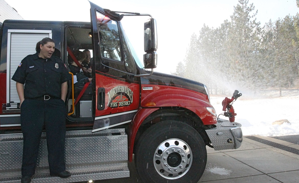 Northern Lakes Fire District firefighter Amanda Tams reacts as Garwood Elementary fifth-grader Abby Van Cleve has fun controlling the sprayer of a water truck with engineer and paramedic Chris Larson on Saturday morning.