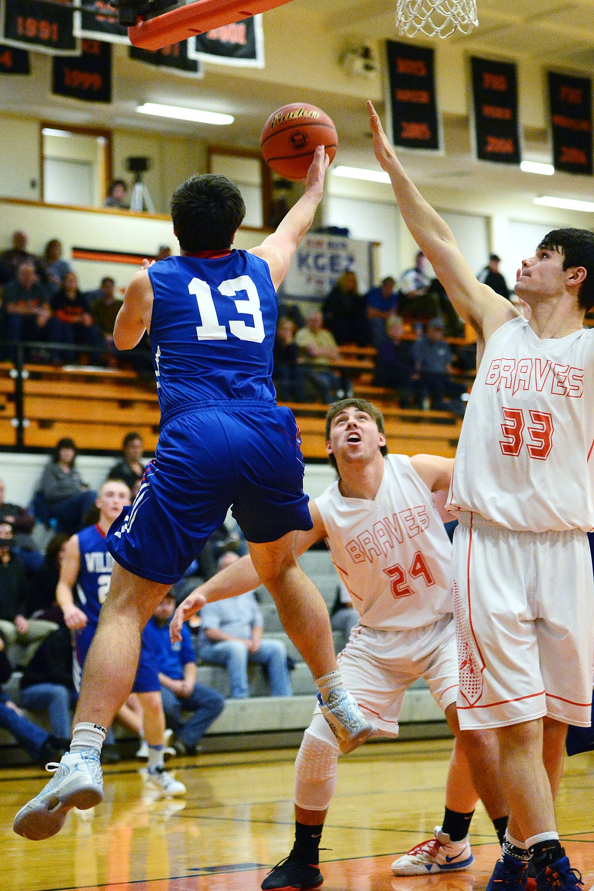 Columbia Falls' Dillon Shipp (13) goes for a reverse layup with Flathead's Blake Counts (24) and Gabe Adams (33) defending at Flathead High School on Saturday. (Casey Kreider/Daily Inter Lake)