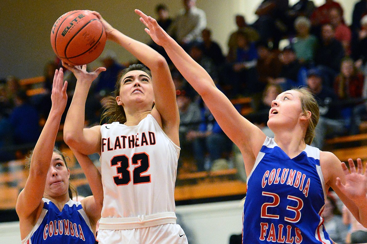 Flathead's Taylor Henley (32) shoots between Columbia Falls defenders Madysen Hoerner (32) and Ryley Kehr (23) at Flathead High School on Saturday. (Casey Kreider/Daily Inter Lake)