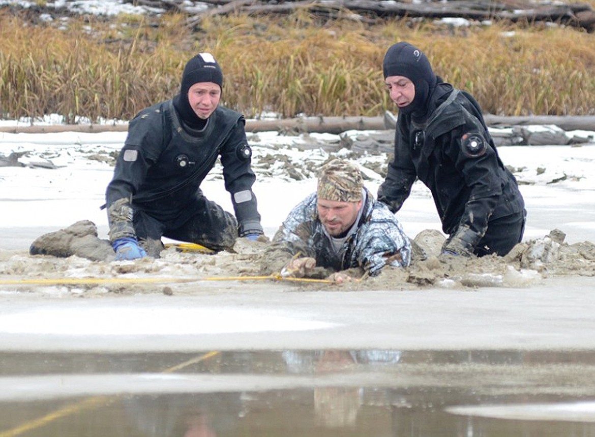 Flathead County Sheriff Chuck Curry, right, and Jordan White, left, work to free a duck hunter who was stuck in the mud Nov. 21, 2012 at Upper Stillwater Lake. (Matt Baldwin/Whitefish Pilot file)