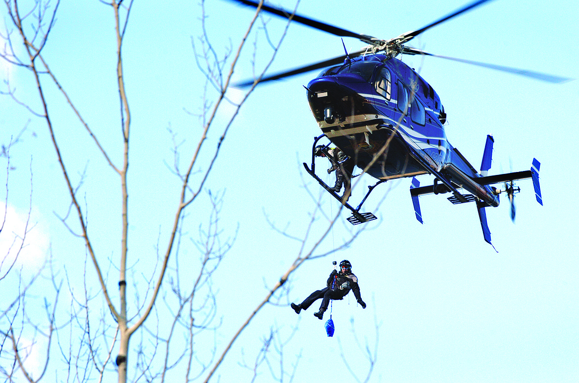 Flathead County Sheriff Chuck Curry hangs below a helicopter March 13, 2014, over the Flathead River near Bigfork. Curry was training with Flathead County Search and Rescue in the recovery of a body of a missing man. (David Reese/Bigfork Eagle file)