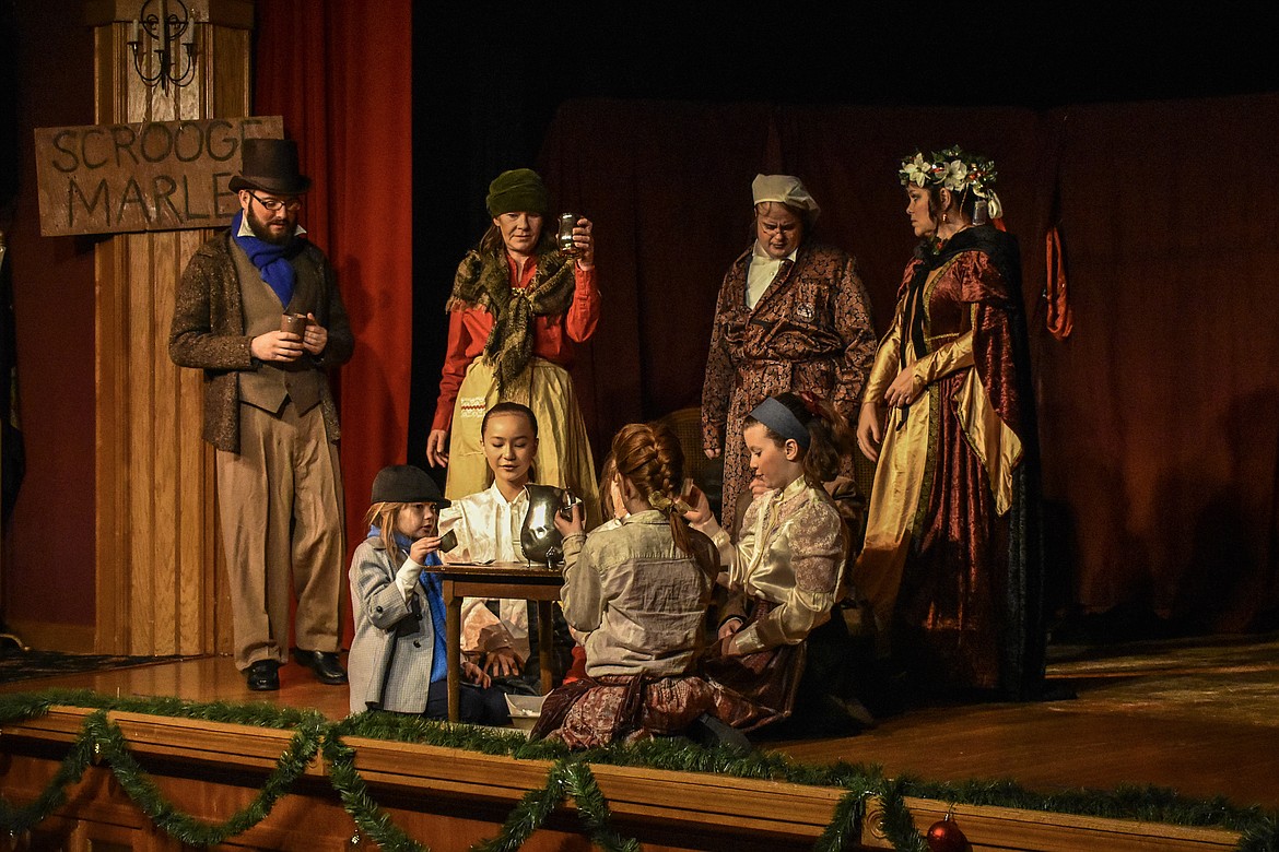 Scrooge, Played by Raymond Miller, shows his shame as the Cratchit family toasts him during his time with the Ghost of Christmas Past, played by Kirsten Koenig, during the Pitiful Players production of A Christmas Carol at the K.W. Maki Theater Sunday. The Cratchit family is played by Elijah Miller (Bob), Theresa Gibson (Mrs. Cratchit), Neveah Neff (Martha), Elena Haugen (Victoria), Mercedes Haugen (Patricia), Katelyn Huff (Belinda), Lily Tankersley (Angie) and Alexandra Durbin (Tiny Tim).  (Ben Kibbey/The Western News)