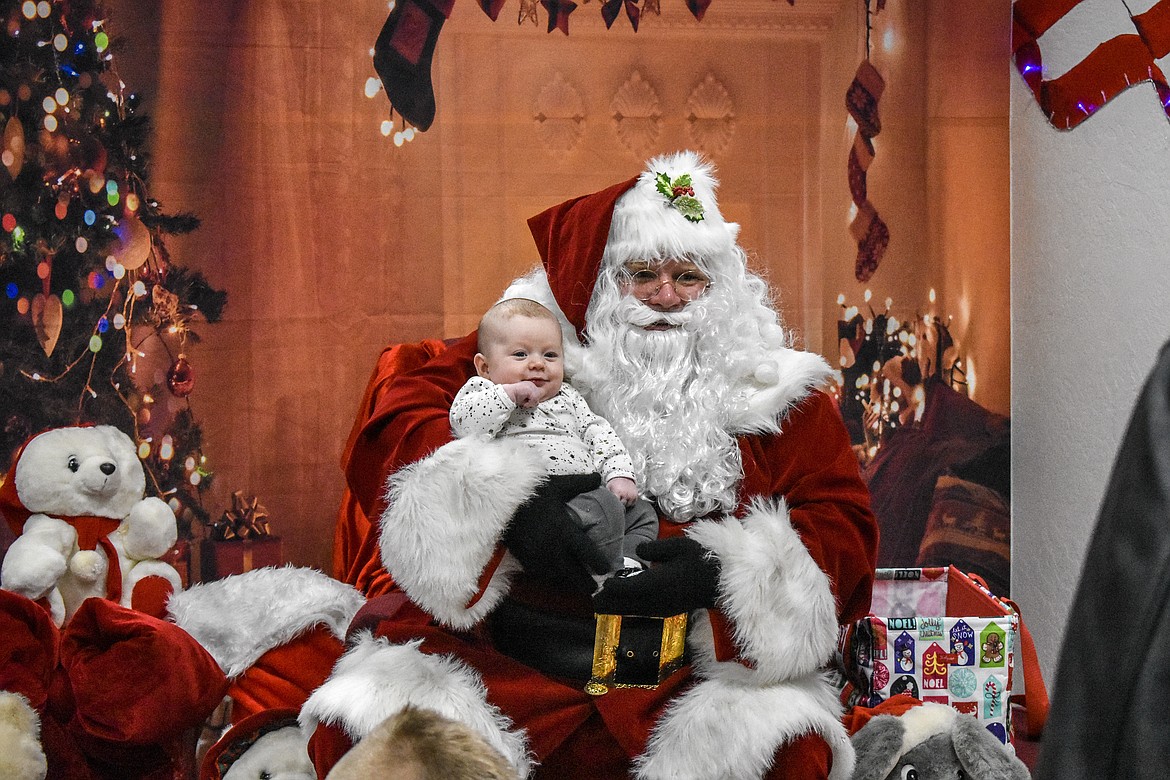 Elijah Sigea sits with Santa Claus at Libby VFW Post 1548 Sunday during the Lincoln County Christmas Annual Toy Giveaway. (Ben Kibbey/The Western News)