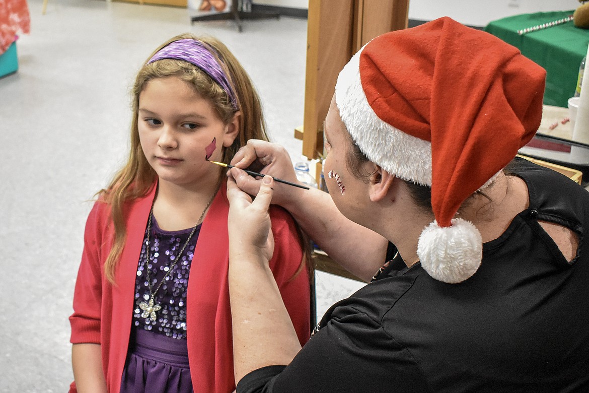 Tabitha Viergutz paints Crystalina Noble at Libby VFW Post 1548 Sunday during the Lincoln County Christmas Annual Toy Giveaway Sunday. (Ben Kibbey/The Western News)