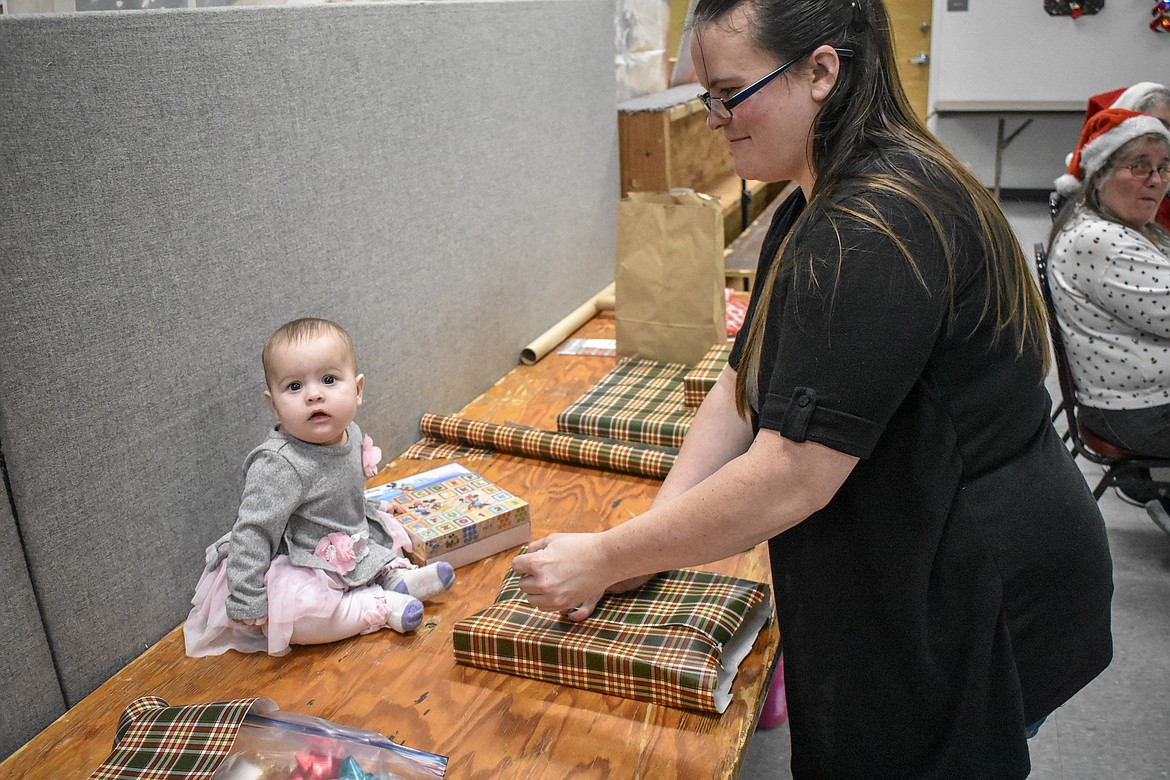 Wendy Noble keeps an eye on her helper, Trinity Noble, while wrapping presents at Libby VFW Post 1548 Sunday during the Lincoln County Christmas Annual Toy Giveaway Sunday. (Ben Kibbey/The Western News)