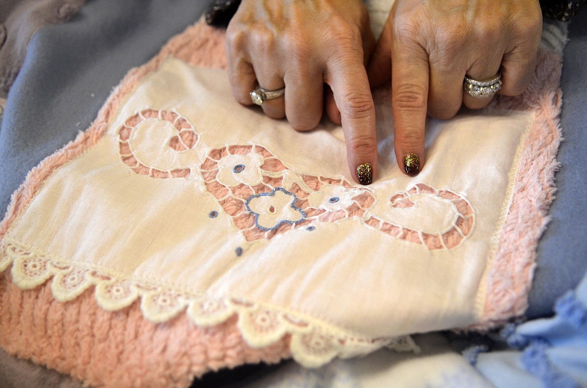 Nancy Khoury  points out the detail that was created in fabric from her grandmother and aunt. The sheets and pillowcases with embroidery and crocheting was incorporated into the quilts. (Heidi Desch/Whitefish Pilot)