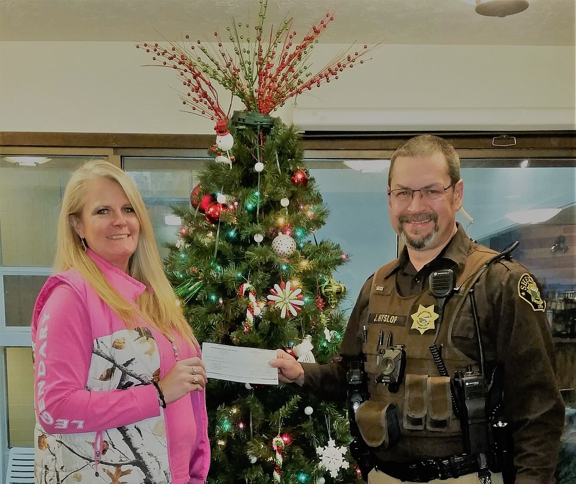 Lincoln County Sheriff’s Deputy John Hyslop receives a check for Shop With a Cop for $1,062.03 from Kootenai Country Montana Foundation Marketing Director Melissa Cady on Dec. 10 at the Venture Inn. The funds were provided through The Venture Inn and Restaurant’s monthly giving program, which provides 10 percent of the restaurant’s proceeds during the last week of each month for charitable giving. (Courtesy photo)
