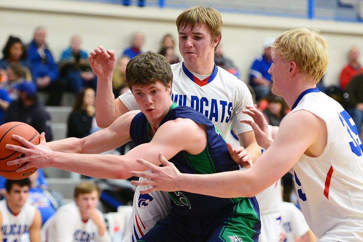 Glacier's Drew Engellant (15) looks to pass under the basket with Columbia Falls' Drew Morgan (12) and Sam Hovde (35) defending at Columbia Falls High School on Thursday. (Casey Kreider/Daily Inter Lake)