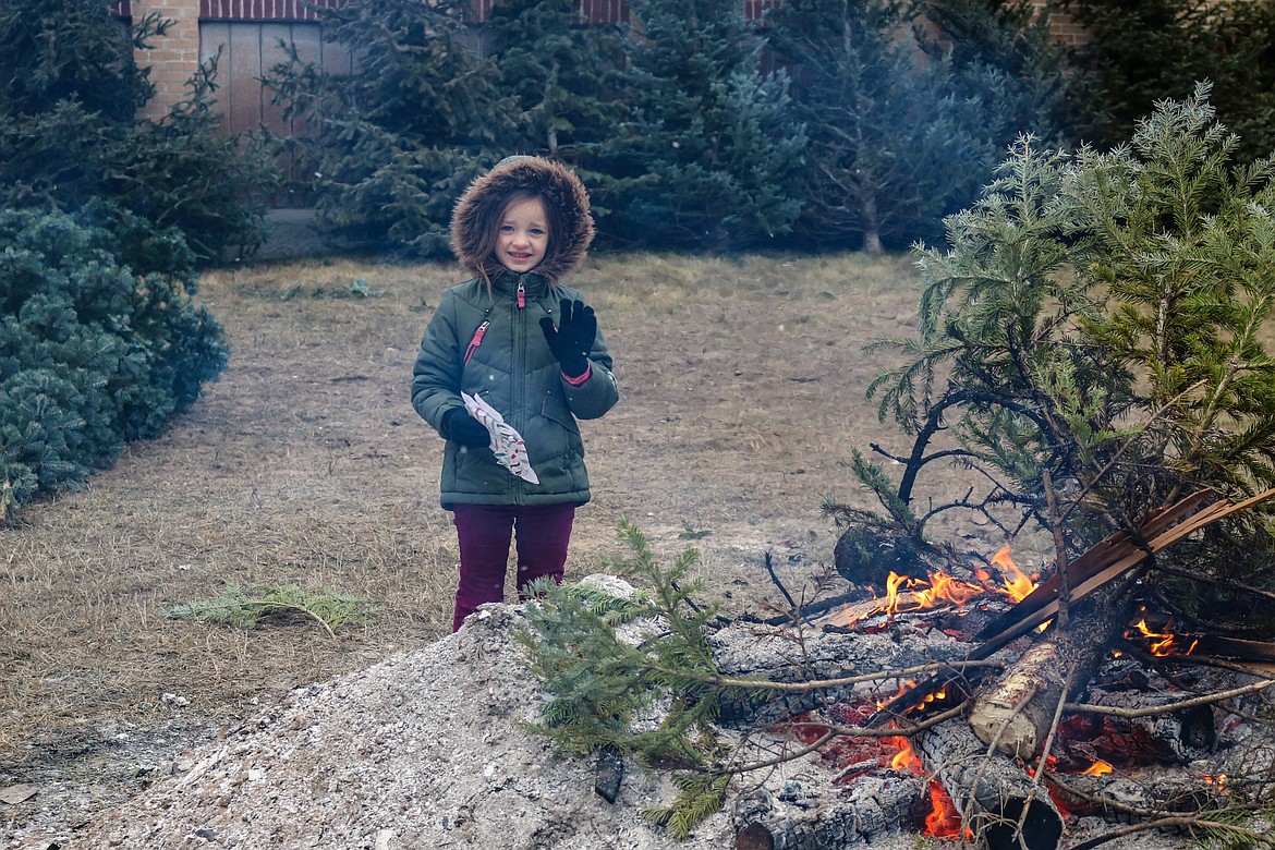 Photo by MANDI BATEMAN
Six-year old Noelle Daniel warms up by the fire while her family picks out a Christmas tree.