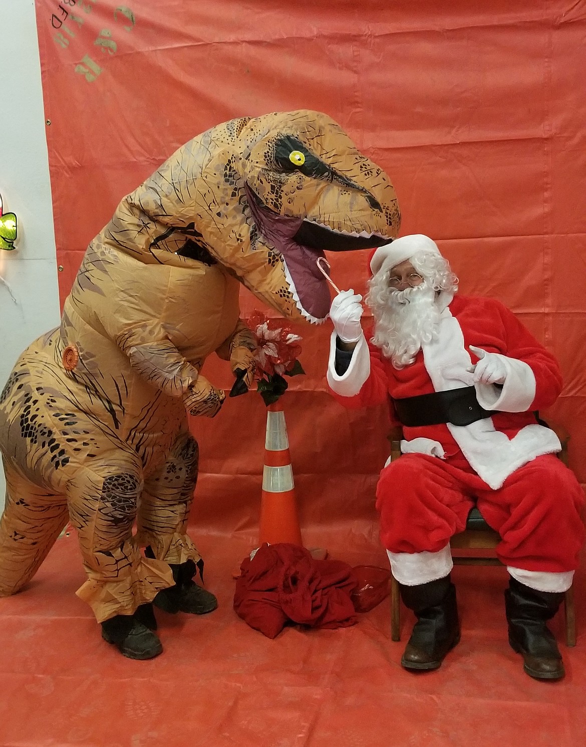 Photo by MANDI BATEMAN
A dinosaur received a candy cane from Santa at North bench Fire station.