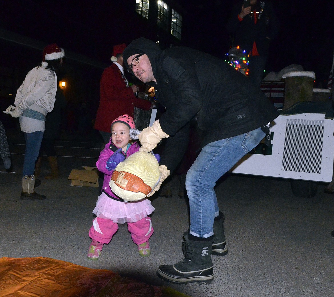 Cecily Farnes, 2, with some assistance from dad Zach, tries out turkey bowling Friday evening on Central Avenue during the annual Whitefish Chamber of Commerce&#146;s Christmas Stroll. (Heidi Desch/Whitefish Pilot)