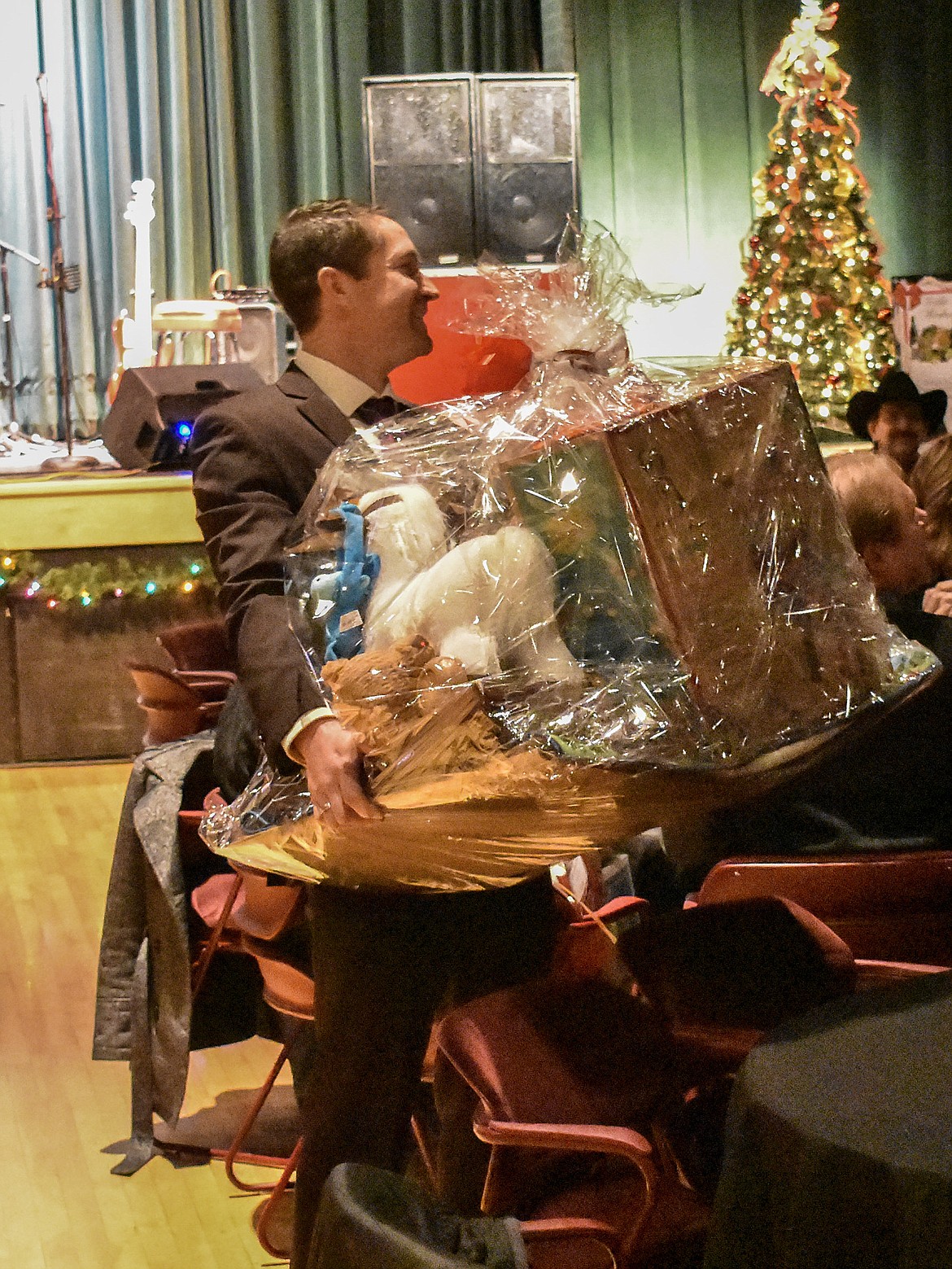 Cabinet Peaks Medical Center Foundation board member Zach Sherbo lugs one of the raffle prizes &#151; a collection of items for a small child &#151; to the lucky winner during the annual Festival of Trees Fundraising Gala for the Cabinet Peaks Medical Center Foundation. (Ben Kibbey/The Western News)