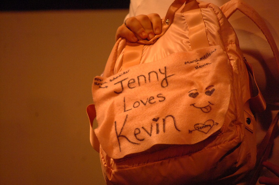 Jenny Partridge (Leena Meckler) holds a backpack with writing by Kevin Schneider (Grace Cockrell), who is pursuing Jenny for his wife.