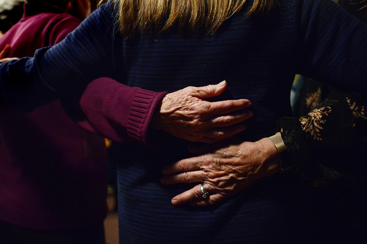 Attendees embrace while singing, dancing and playing instruments at Dances of Universal Peace at Shining Mountains Center for Spiritual Living in Kalispell on Wednesday, Dec. 19. (Casey Kreider/Daily Inter Lake)