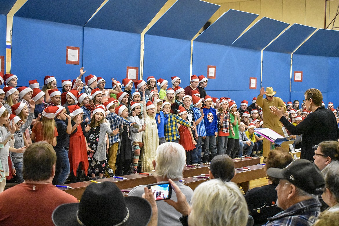 With a little help from reindeer and art teacher Kyle Hannah, Libby Public School music teacher Lorraine Braun leads 4th and 5th grade students in song during their Christmas concert at the Libby Elementary School Gym Thursday. (Ben Kibbey/The Western News)