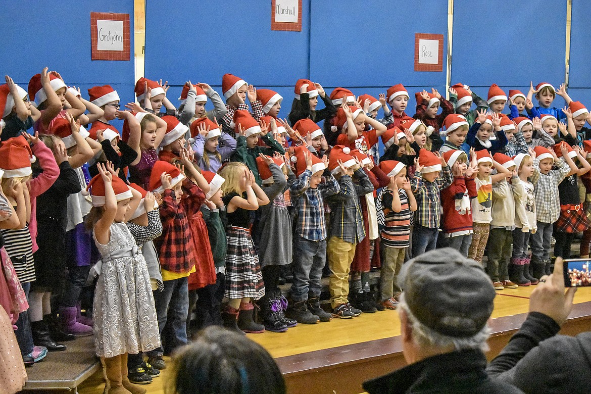Libby Elementary School students make reindeer antlers with their hands during the kindergarten and 2nd grade Christmas concert at the Libby Elementary School Gym Thursday. (Ben Kibbey/The Western News)