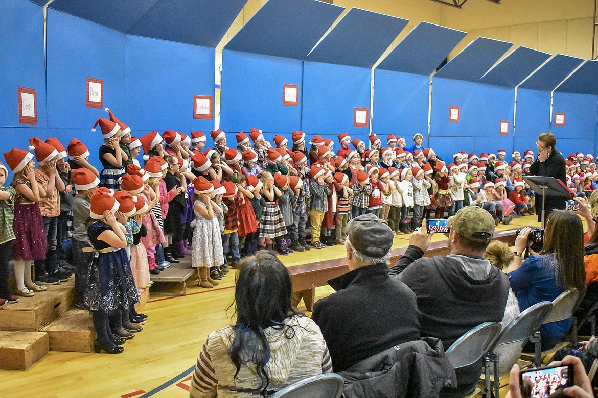 Led by Libby Public School music teacher Lorraine Braun, kindergarten and 2nd grade students make the motion for sleep during their Christmas concert at the Libby Elementary School Gym Thursday. (Ben Kibbey/The Western News)