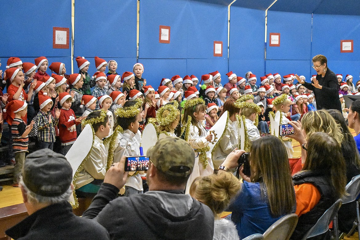 Libby Public School music teacher Lorraine Braun leads the kindergarten and 2nd grade students in song during their Christmas concert at the Libby Elementary School Gym Thursday. (Ben Kibbey/The Western News)