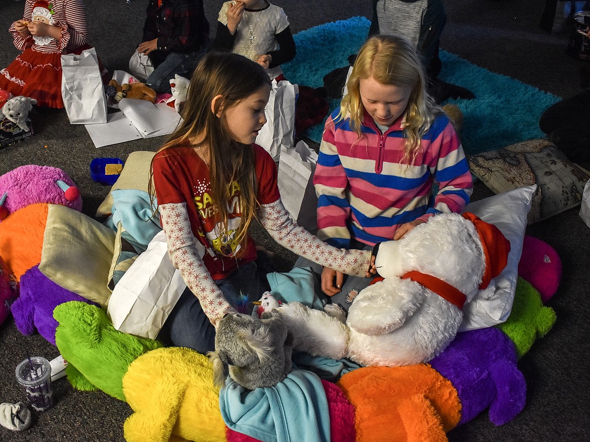 Sabrina Thurston admires the bear that Santa brought for Emma Rose Roberts as the children go through their candy at McCormick Elementary School on Friday during Sata’s visit with members of Troy VFW Post 5514. (Ben Kibbey/The Western News)