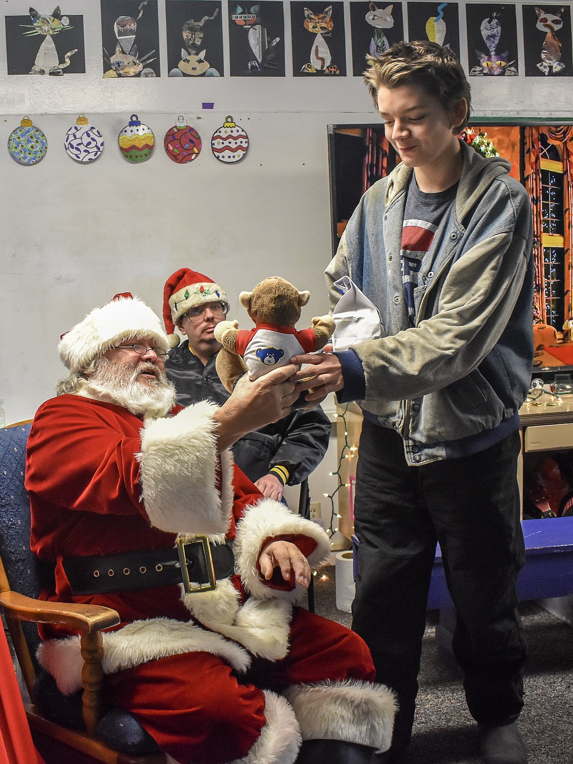 McCormick Elementary School 8th grade student Evin Thurston accepts a stuffed teddy bear from Santa on Friday during Santa&#146;s visit along with members of Troy VFW Post 5514. (Ben Kibbey/The Western News)
