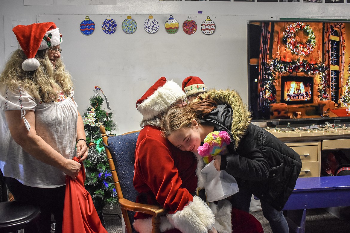 Santa gets a hug from 8th grade student EmmaLea White-Carlson at the McCormick Elementary School on Friday as VFW Post 5514 Auxiliary President Francine Ninneman looks on. (Ben Kibbey/The Western News)