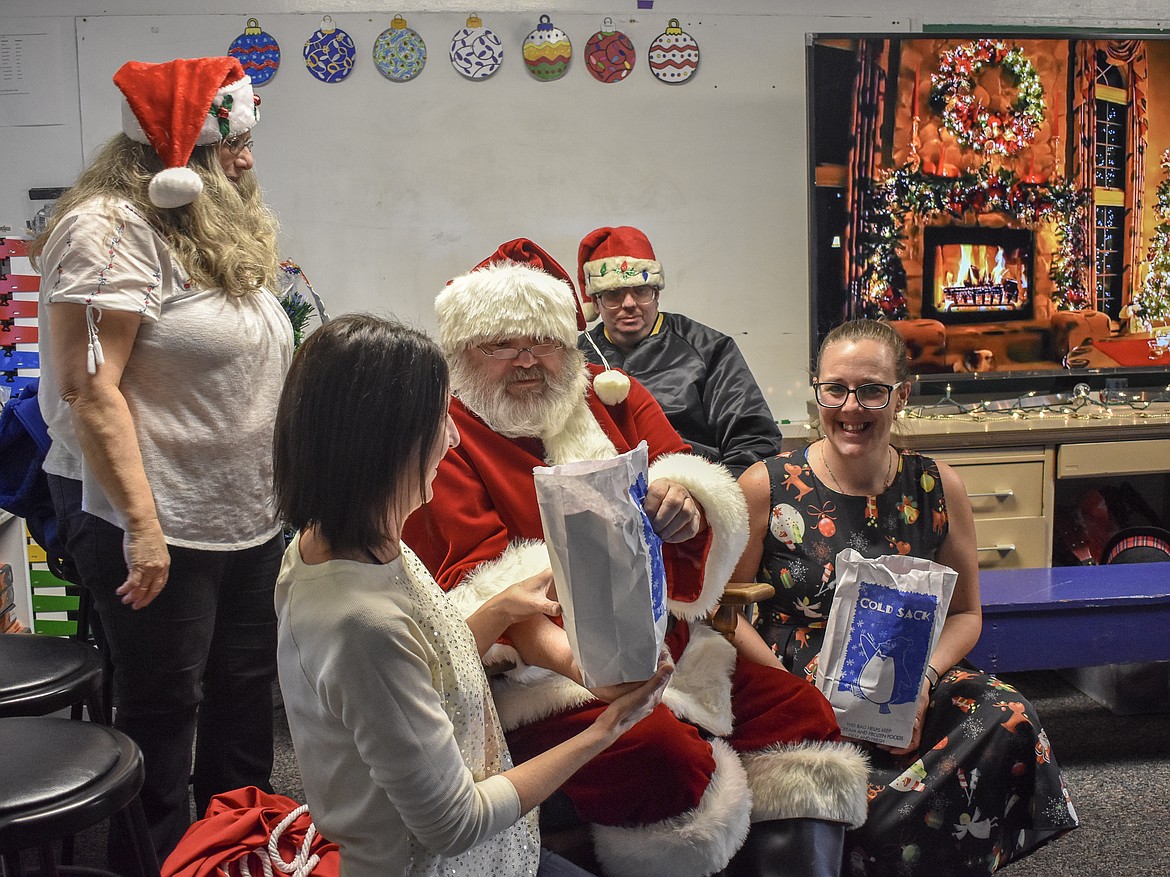 McCormick Elementary School teachers Nikki Eide and Stephani Wallace get in on the fun -- and the candy -- Friday during Santa&#146;s visit along with members of Troy VFW Post 5514. (Ben Kibbey/The Western News)
