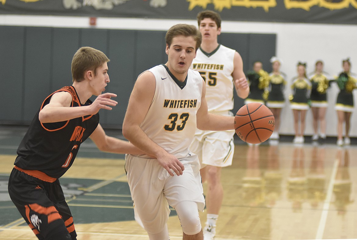 Bulldog Ryan Kemm dribbles the ball around a Frenchtown defender in the first half on Dec. 21 in the gym at Whitefish High School. (Heidi Desch/Whitefish Pilot)