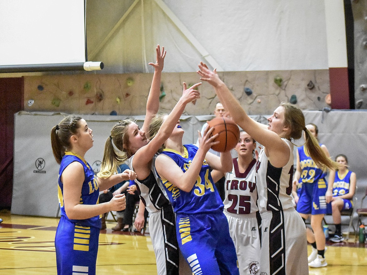 Troy juniors Katelyn Tallmadge and Ella Pierce fight to keep Libby junior McKenzie Proffitt from the basket moments before Proffitt scored in the fourth quarter at Troy Tuesday. (Ben Kibbey/The Western News)