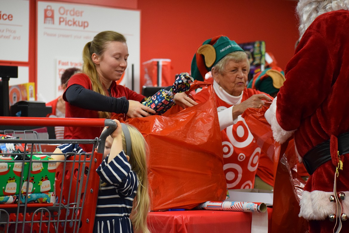 Sgt. Audrey Darnall of the Idaho Army National Guard and Target team member Diane Kosonen bundle presents into bags destined for underneath family Christmas trees as part of the &#147;Heroes and Helpers&#148; event early Tuesday morning at the Coeur d&#146;Alene Target store. (ANDREW ENRIQUEZ/Courtesy)