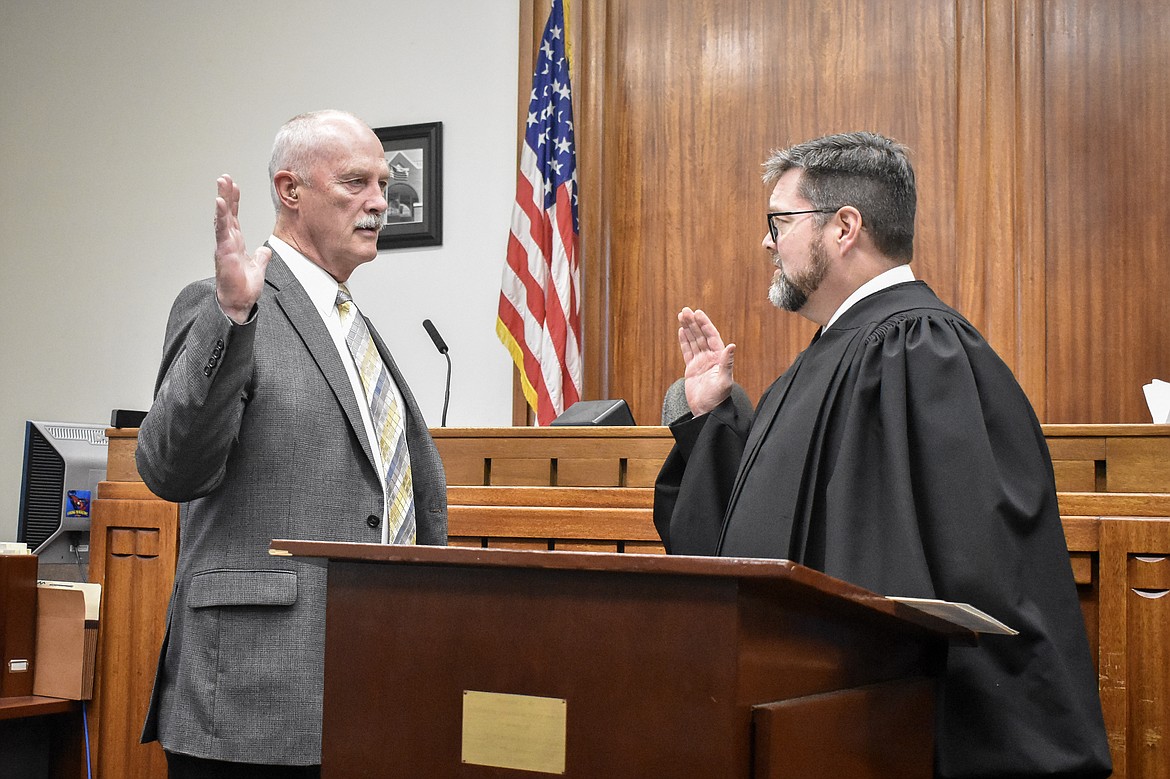 Montana 19th Judicial District Judge Matt Cuffe swears in Lincoln County Coroner Steven Schnackenberg in the County Courthouse Wednesday. (Ben Kibbey/The Western News)